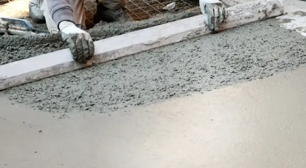 Pracownik wyrównuje świeży beton na fundament. Odpowiedni beton na fundament to klucz do trwałości konstrukcji.