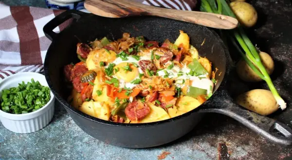 Herzhafte Bauernpfanne mit Ei, Kartoffeln, Wurst und Gemüse, garniert mit Schnittlauch. Ein deftiges Gericht für jeden Tag.