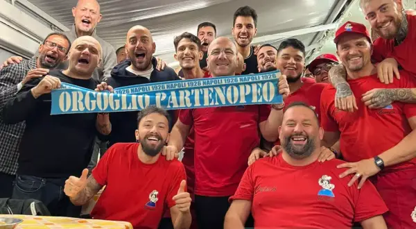 Un gruppo di tifosi esulta con una sciarpa "Orgoglio Partenopeo" e magliette con scritto "Nennella Napoli".