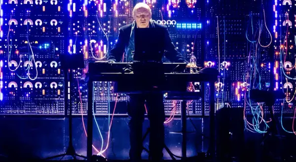Hans Zimmer w Krakowie, na tle świecącej ściany syntezatorów i kabli, tworzy magiczną atmosferę.