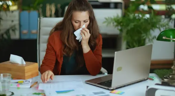 Kobieta z katarem pracuje przy biurku, zastanawiając się, czy na umowie zlecenie jest L4.