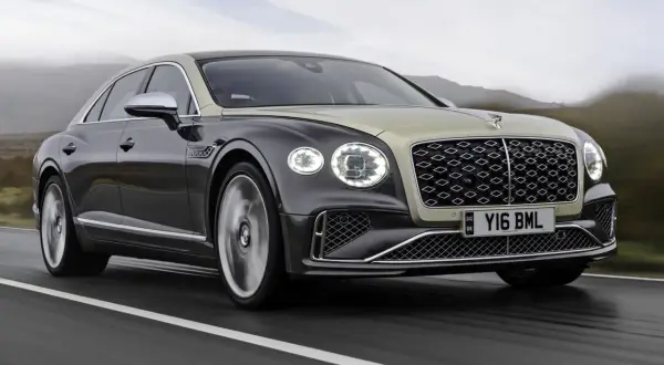Elegancki Bentley Flying Spur w dwukolorowym malowaniu pędzi po drodze. Sprawdź, jaka jest aktualna bentley cena.
