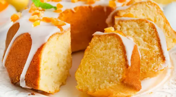 Puszysta babka wielkanocna cytrynowa, polana lukrem i posypana kandyzowaną skórką cytrynową, prezentuje się apetycznie.