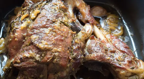 Succulento agnello al forno, dorato e profumato con rosmarino e aglio, pronto per essere gustato.