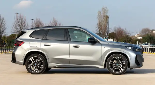 Srebrny, niezawodny SUV BMW X1 stoi na parkingu. Elegancki design i sportowe felgi podkreślają jego charakter.