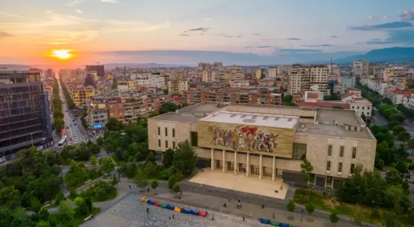 Zachód słońca nad Tirana, stolicą Albanii. Widok na plac z kolorowymi pufami i budynek z mozaiką.