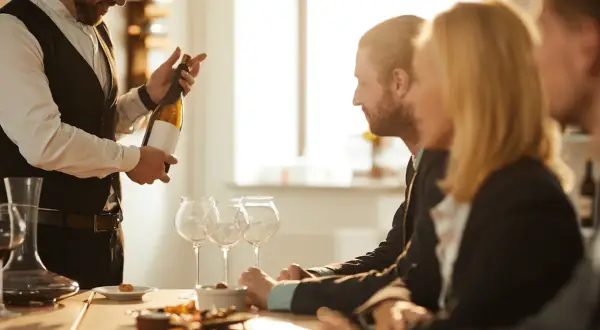 Ein Sommelier präsentiert eine Weinflasche. Seine Expertise zeigt die wahre sommelier bedeutung.