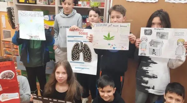 Dzieci prezentują plakaty o szkodliwości używek, pokazując jak zrobić projekt artystyczno-edukacyjny.