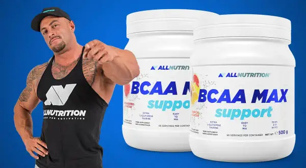 Muskularny mężczyzna w czapce i koszulce Allnutrition wskazuje palcem na dwa słoiki suplementu BCAA MAX.