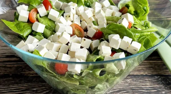 Sałatka z kostkami tofu, która smakuje jak feta. Zielona sałata, pomidorki koktajlowe i tofu w szklanej misie.