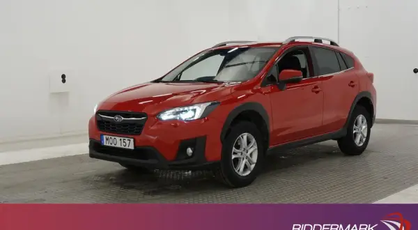 A red Subaru XV parked indoors, with its headlights on.