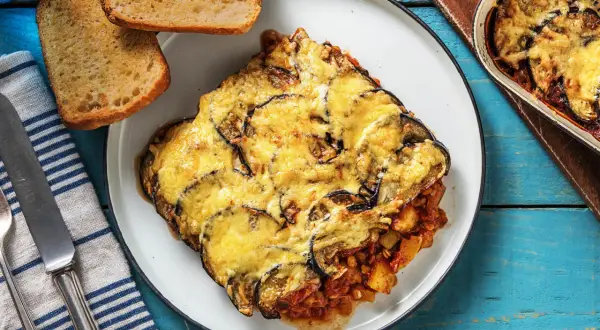 Une part généreuse de moussaka végétarienne, gratinée au fromage, servie avec du pain grillé. Un plat réconfortant et savoureux.