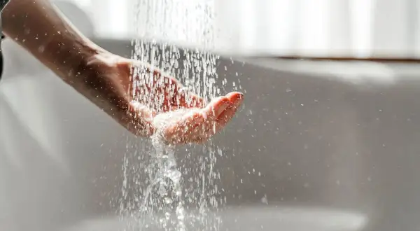Hand fängt Wasser auf. Mögliche Legionellen im Wasser können zu einer Mietminderung führen.