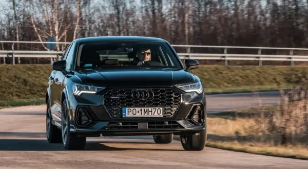 Czarny q3 audi pędzi po drodze, kierowca w okularach obserwuje trasę.