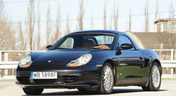 Czarny Porsche Boxster 986 z beżowym wnętrzem, gotowy na wiosenne przejażdżki.