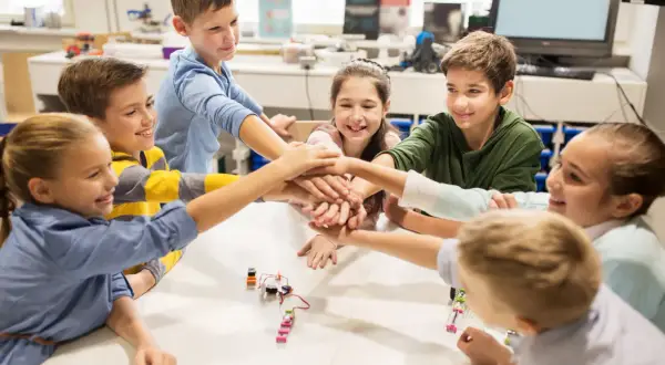 Kinder legen ihre Hände in der Mitte zusammen, ein Zeichen für Teamwork in ihrem mint kita-Projekt.