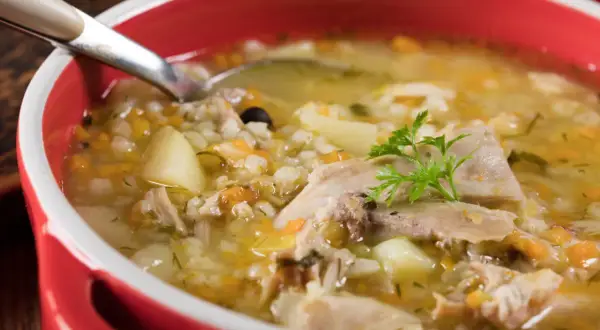 Gorący krupnik, przepis babci, z kawałkami mięsa, ziemniaków i kaszy pęczak, ozdobiony natką pietruszki.