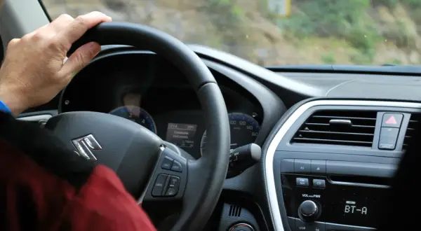 Ręka na kierownicy Suzuki. Rozpoczynają się formalności związane z kupnem używanego samochodu, czas na jazdę próbną.