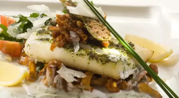 Wykwintne danie z rybą halibut, podane z kurkami, pomidorkami i cytryną.