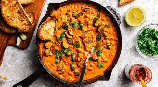 Herzhafte zucchini pfanne in cremiger Sauce, garniert mit frischer Petersilie und serviert mit geröstetem Brot.