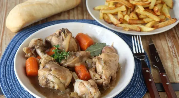 Guiso de pollo con patatas de la abuela, tierno y jugoso, acompañado de patatas fritas crujientes y pan.