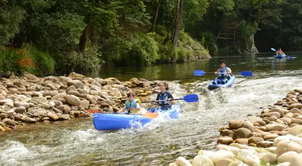 Familias disfrutan del kayak por donde pasa el río Sella, rodeados de naturaleza exuberante y aguas cristalinas.