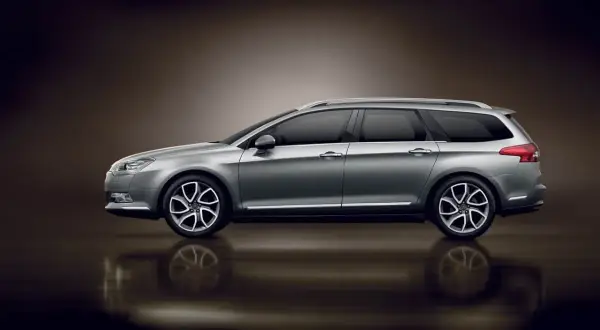 Srebrny Citroen C5 X7 kombi z przyciemnianymi szybami i eleganckimi felgami, odbijający się od błyszczącej powierzchni.