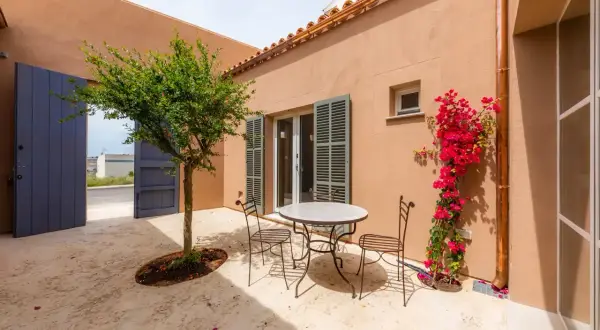 Un patio andaluz con mesa y sillas de hierro forjado, un árbol frutal y buganvillas. Ideas para un oasis mediterráneo.