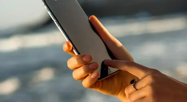 Dłoń z pierścionkiem pokazuje, jak włączyć iPhone'a, dotykając ekranu.
