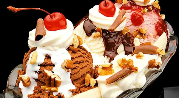 En klassisk banana split med tre kulor glass, banan, grädde, chokladsås, nötter och körsbär. Ett perfekt banana split recept för en varm dag.