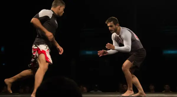 Two fighters face off, their stances showing the endurance and stamina required for this intense grappling match.