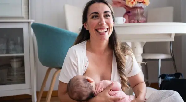 Szczęśliwa mama karmi piersią dziecko, pokazując jedną z wielu zalet karmienia piersią.