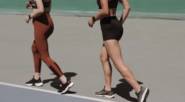 Deux femmes courent sur une piste, visant à marcher 8 km par jour pour leur entraînement.