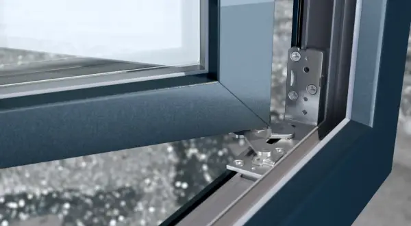 Mechanizm drzwi balkonowych nie chce się zamknąć. Widoczny metalowy zawias i fragment ramy okiennej.