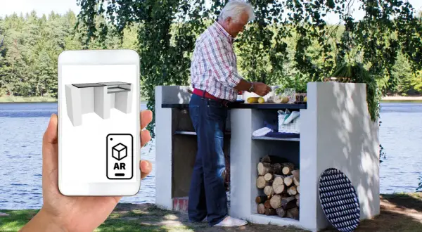 En man förbereder mat vid en murad grill vid en sjö. En telefon visar en 3D-modell av en Murad grill i AR.