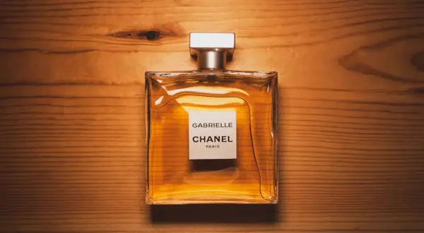 Elegancka butelka perfum Chanel Gabrielle na drewnianym tle. Czy to właśnie takich perfum używają gwiazdy?