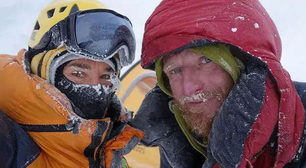 Tomasz Mackiewicz und ein Bergsteigerkollege, bedeckt mit Schnee, blicken in die Kamera.