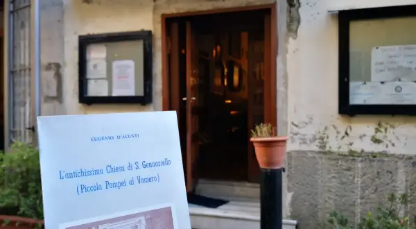 Un cartello annuncia "L'antichissima Chiesa di S. Gennariello (Piccola Pompei al Vomero)" davanti a un ingresso antico.