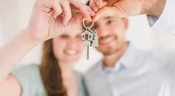 Coppia felice mostra le chiavi di casa, un promemoria delle 10 cose da sapere prima di comprare casa.