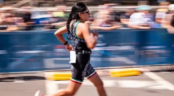 A woman in a triathlon suit, her hair in braids, runs with determination. This is the essence of Ironman training.