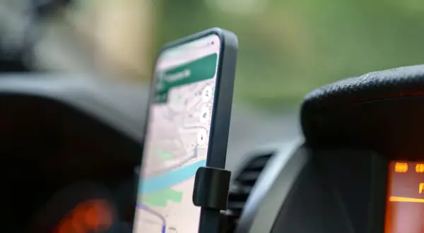 Telefon z mapą na ekranie, zamontowany w samochodzie. Ułatwia nawigację na telefon podczas podróży.