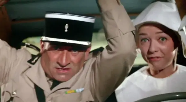 Louis de Funès w filmach, w mundurze żandarma, z przerażoną miną obok kobiety w białym nakryciu głowy.