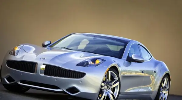 Srebrny Fisker Karma z charakterystycznym grillem i reflektorami, lśniącym lakierem i stylowymi felgami.