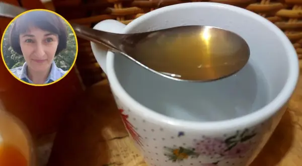 Kobieta z uśmiechem na twarzy pokazuje łyżkę z wodą z octem jabłkowym, gotową do wypicia.