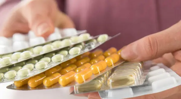 Hände halten mehrere Blisterpackungen mit Tabletten und Kapseln. Die Frage, darf man Tabletten mit ins Flugzeug nehmen, wird hier visuell thematisiert.