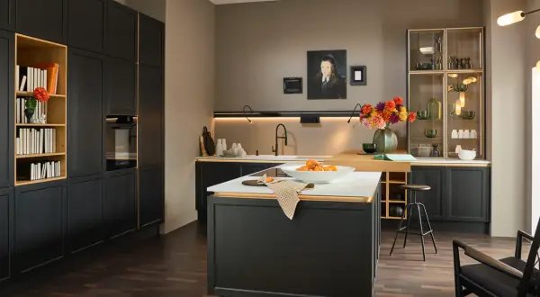 Cucina moderna con mobili neri e dettagli dorati, un'isola centrale con frutta e un tappeto dai colori caldi che aggiunge un tocco accogliente.