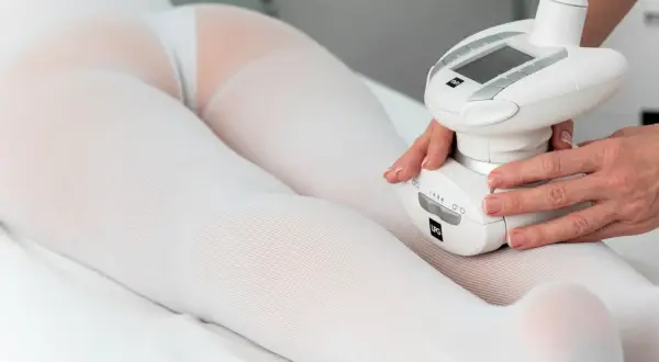 Zabieg endermologii na nogi i pośladki w białej bieliźnie zabiegowej.