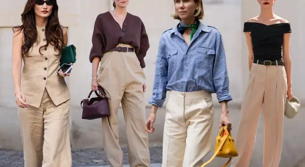 Quattro donne sfoggiano eleganti pantaloni color fango, dimostrando versatili abbinamenti uomo e donna per un look chic.