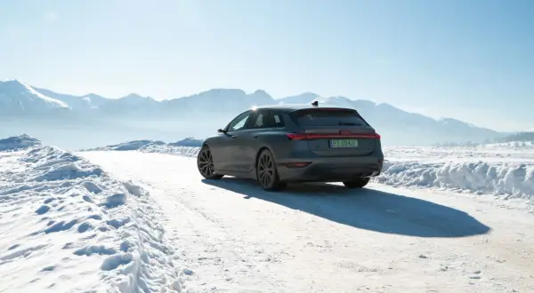 Audi A6 e-tron na śnieżnej drodze z górami w tle.