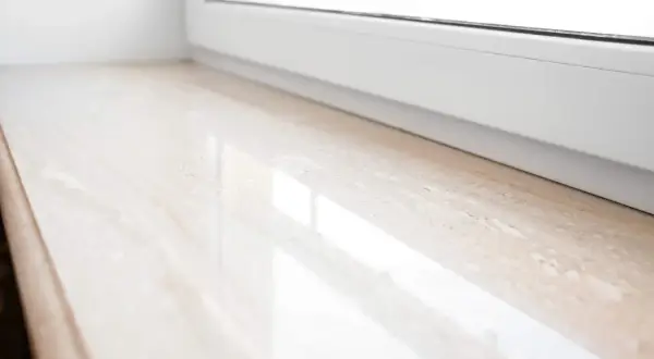 Jasny parapet z konglomeratu, z subtelnymi żyłkami, odbija światło. Wybór między parapetem mdf czy konglomerat jest ważny dla estetyki wnętrza.